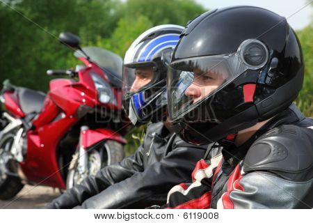 Closeup dva motocyklisté sedí na venkovské silnici poblíž kola