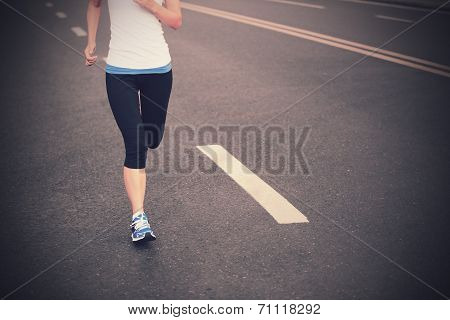 Runner athlete running on city road. woman fitness jogging workout wellness concept.
