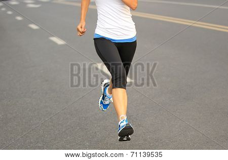 Runner athlete running on city road. woman fitness jogging workout wellness concept.