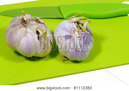 Garlic bulbs on a green cutting board