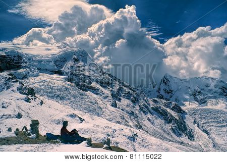 Young hiker sitting in south american Andes in Peru Ausangate with dramatic clouds forming above the mountains