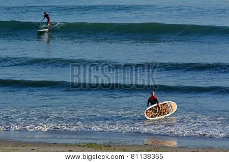 People Surf On Stand Up Pedal Board