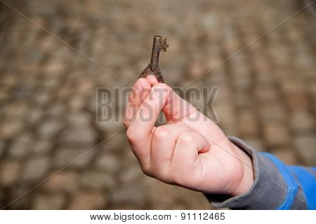 Child's Hand Holding One Old Key