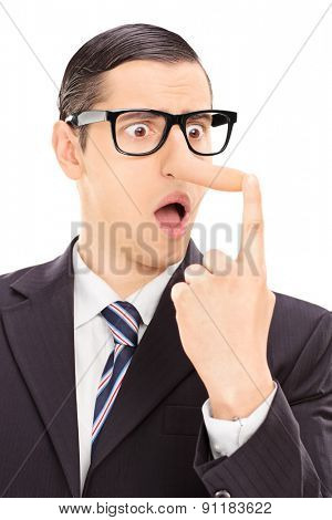 Vertical shot of a young displeased businessman looking at his long nose and trying to put it back with his finger isolated on white background