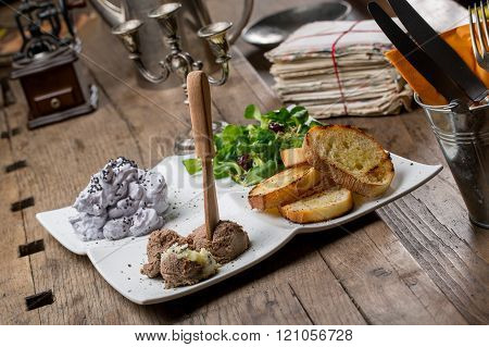Tasty appetizers with chicken liver pate valerian salad toasted bread and blueberry mousse on an old wooden table