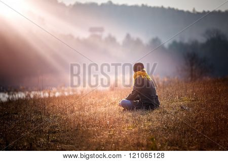Young Woman Sitting On Grass On Meadow