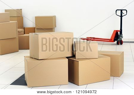 Stack of carton boxes and manual pallet truck indoors