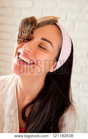 portrait of young smiling darkhaired woman with snails achatina giant on her face