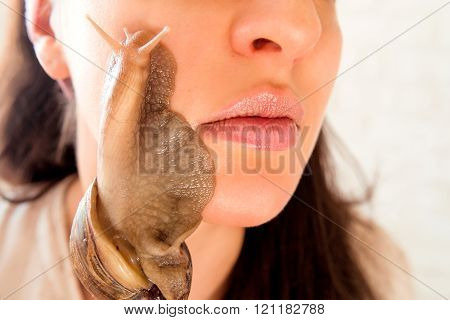 portrait of young darkhaired woman with snails achatina giant on her face