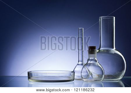 Assorted empty laboratory glassware, test-tubes. Blue tone medical background. Copy space for text.