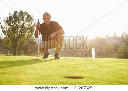 Male Golfer Lining Up Putt On Green