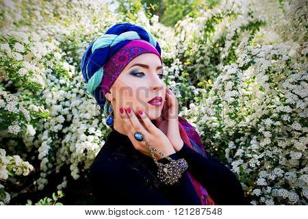 portrait of the beautiful girl in a turban on the flowers of spirea background