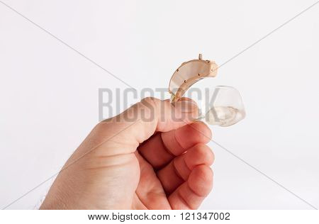 Hand holding an used hearing aid with ear mould
