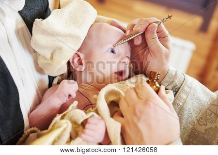 chrismation sacrament of newborn baby during christening 