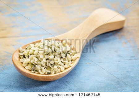 hemp seed hearts on a wooden spoon against blue painted grunge wood