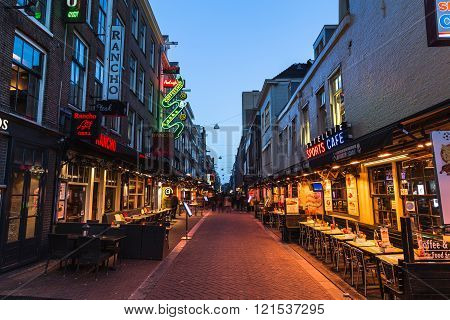 AMSTERDAM NETHERLANDS - 16TH FEBRUARY 2016: A view down Korte Leidsedwarsstraat in Amsterdam at night. A Coffee Shop restaurants and people can be seen.
