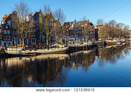 AMSTERDAM NETHERLANDS - 16TH FEBRUARY 2016: A view along the Waalseilandgracht Canal in Amsterdam at twilight. Building boats and reflections can be seen.