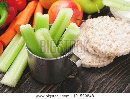 Celery in a mug close-up with fruits and vegetables. Healthy food background