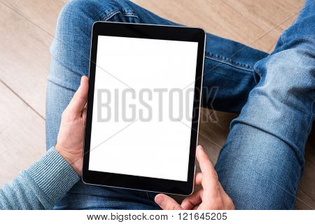 Man using tablet computer while sitting on a wooden floor. View from above. Clipping path included.