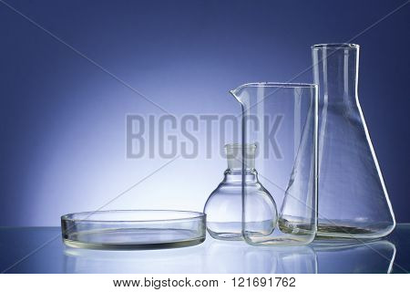 Assorted empty laboratory glassware, test-tubes. Blue tone medical background. Copy space for text.