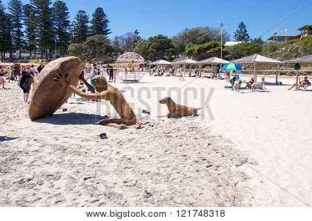 COTTESLOE,WA,AUSTRALIA-MARCH 12,2016:  Stone human figure and dog sculpture with tourists at the 