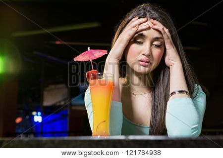 Depressed woman having cocktail drink at bar counter in bar
