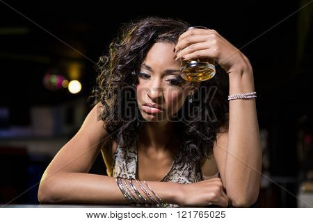 Depressed woman having whiskey drink at bar counter in bar
