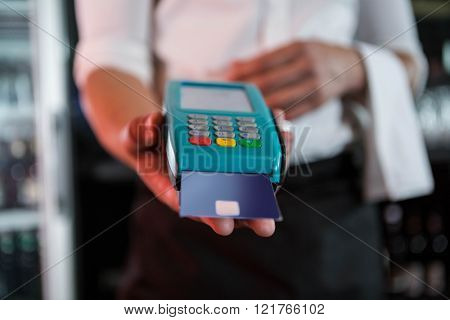 Bartender accepting a credit card at bar counter in bar