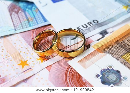 Golden wedding rings on euro banknotes background. Marriage of convenience