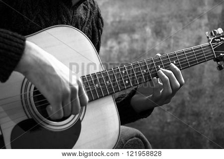 young man playing an acoustic guitar on the background of a concrete wall.
** Note: Shallow depth of field