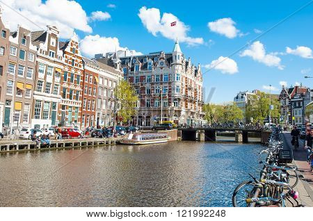 Amsterdam-April 30: Rokin canal with bikes parked along the bank Hotel de l'Europe is visible in the background tourists enjoy cityscape on the opposite side on April 30 2015 the Netherlands.