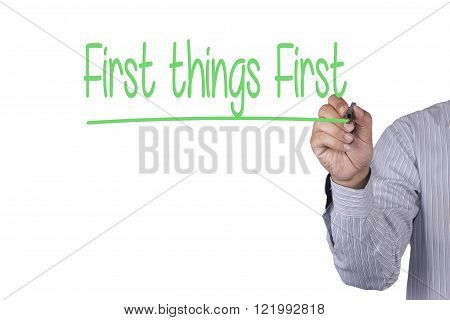 Man Hand writing First Things First with black marker on visual screen. Isolated on white. Business technology internet concept. Stock Photo