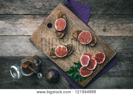 Sliced Figs And Bread With Jam On Choppingboard In Rustic Style