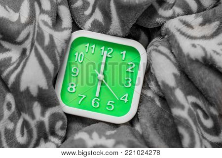 Green alarm clock on the bed. It alarm at 6.00 AM on workday.Time for sunrise.Process with monotone.
