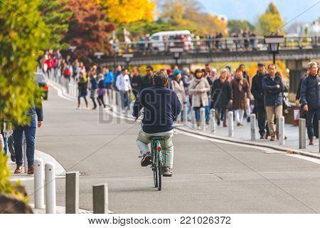 KYOTO, JAPAN - NOVEMBER 24, 2016 Biker cyclists on a street near the Togetsukyo Bridge and many people come to visit  autumn season, Arashiyama, Kyoto, Japan.