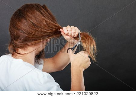 Trim and cut concept. Young handsome man cutting his hair. Change of look.  Barber and hairdresser. Back view.