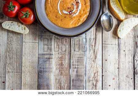 Homemade cream of tomato soup served in bowl on rustic ooden background, Top view