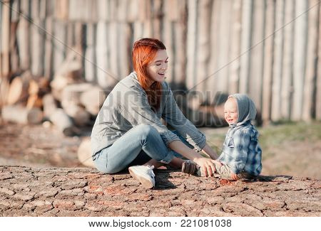 Mother with baby in nature sitting on against each other and laughing