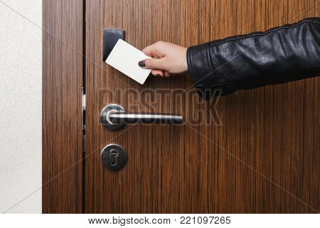 Hand inserting key card in electronic lock. Woman opening hotel room door. Privacy, security, personal identification concept, copy space