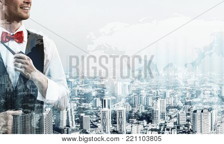 Double exposure of confident and young businessman in smart-casual wear smoking pipe and modern cityscape with business and media interface. Concept of new technologies for modern business.