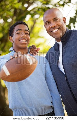 African American father and son playing fooball.
