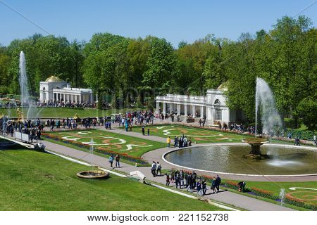 PETERHOF, ST. PETERSBURG, RUSSIA - JUNE 4, 2017: Tourists walking around the French fountain and the Grand Cascade. The cascade was built in 1715-1724