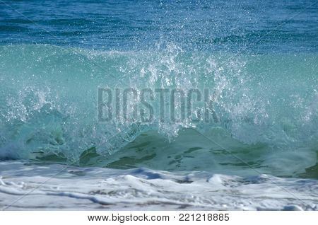 Waves breaking on the shore showing spray