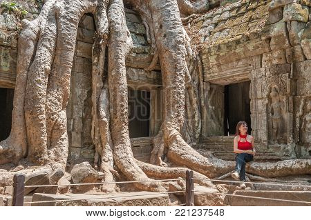 SIEM REAP, CAMBODIA - MARCH 9, 2009: Tourist posing at Ta Prohm in Siem Reap. Built in 12-13th century Ta Prohm was later the location for the movie Tomb Raider.