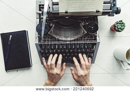 Writer typing with retro writing machine. View from above.