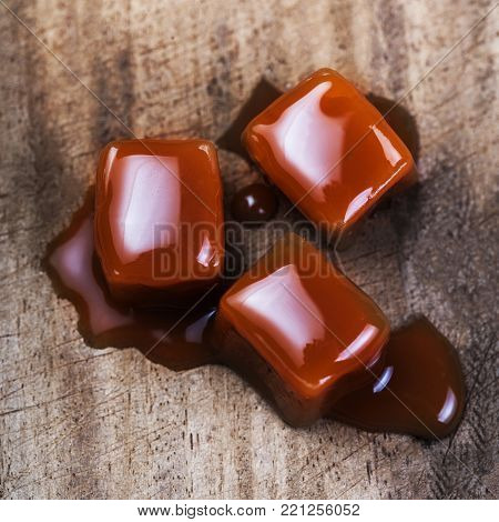 Organic caramel candies and caramel sauce on wooden background, Golden Butterscotch toffee caramels