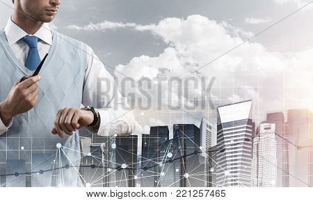 Double exposure of confident and young businessman in smart-casual wear smoking pipe and modern cityscape with business and media interface. Concept networking for modern business.
