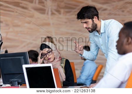diverse college students using laptop and talking, learning exchanging ideas.