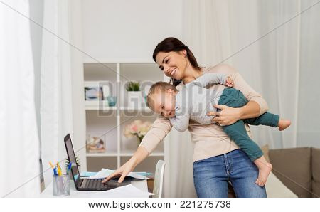 motherhood, multi-tasking, family and technology concept - happy mother with baby, laptop computer and papers working at home
