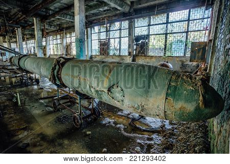 Old rusted submarine torpedoes in abandoned torpedo factory.